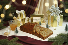 Load image into Gallery viewer, Banana bread with honey, a jar of jam, and decorative items on a white surface.